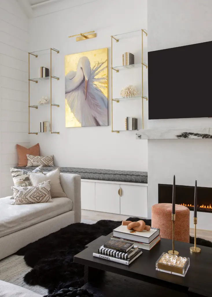 Our Southern interior designers created a contemporary coastal color palette in this living room through the bold black coffee table, plush beige couches, gold home decor accents, coral accent pillows, and the soft yet colorful crane paintings that anchor the room's interior design.