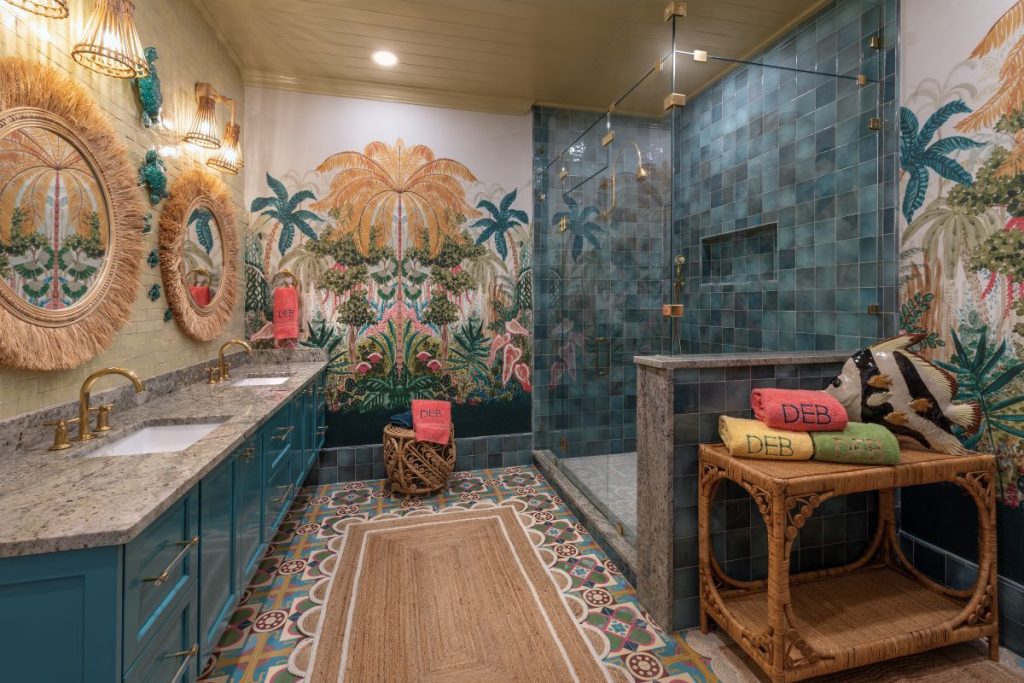 Palm Beach style bathroom with tropical murals, teal tile and cabinetry, patterned floors, and woven furnishings