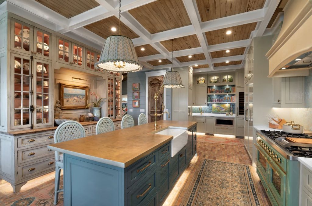 Palm Beach interiors kitchen with blue cabinetry, dual islands, glass-front cabinets, and a coffered wood ceiling.