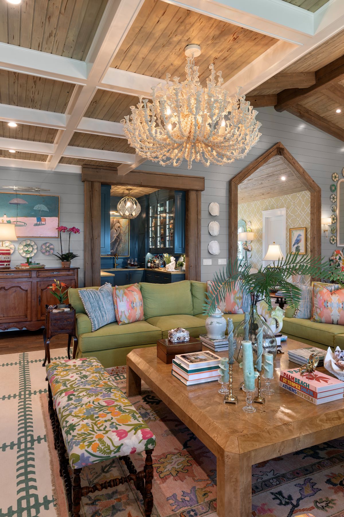 Contemporary 50s-style Palm Beach interiors living room with green sofas, floral seating, a large wood coffee table, and a statement chandelier