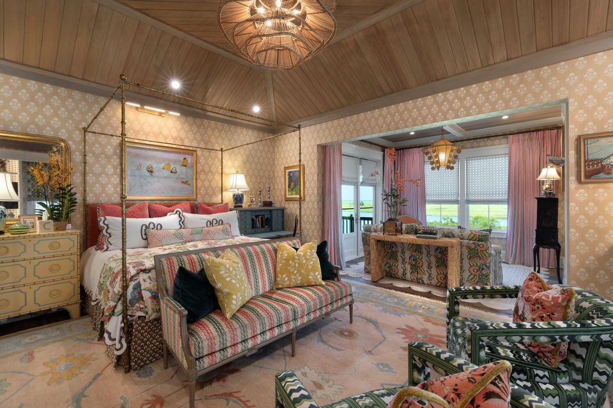 Palm Beach interiors bedroom with colorful patterned furnishings, a canopy bed, wood-paneled ceiling, and waterfront views
